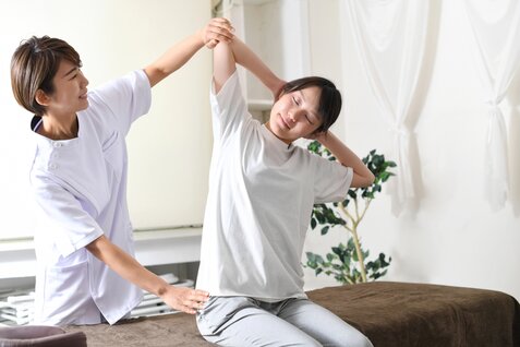 オフィスで肩のストレッチをしている女性